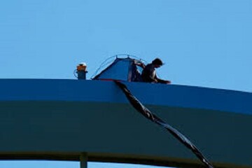 VIDEO: A man climbs to top of bridge to protest war on Iran