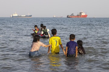 Children play in the shallow coastal waters off Bandar Abbas in Iran’s Hormozgan province, near the strategic Strait of Hormuz, as ships pass in the distance along one of the world’s most vital maritime corridors, on Monday, June 1, 2026.
